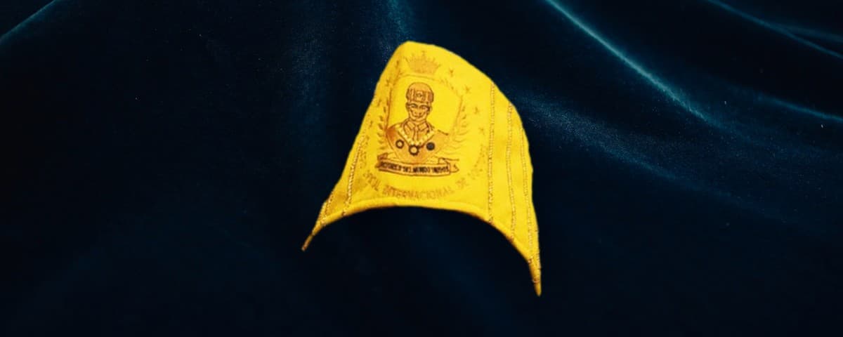 Birrete dorado de la colegiatura de Doctor Académico, con el escudo del colegio bordado